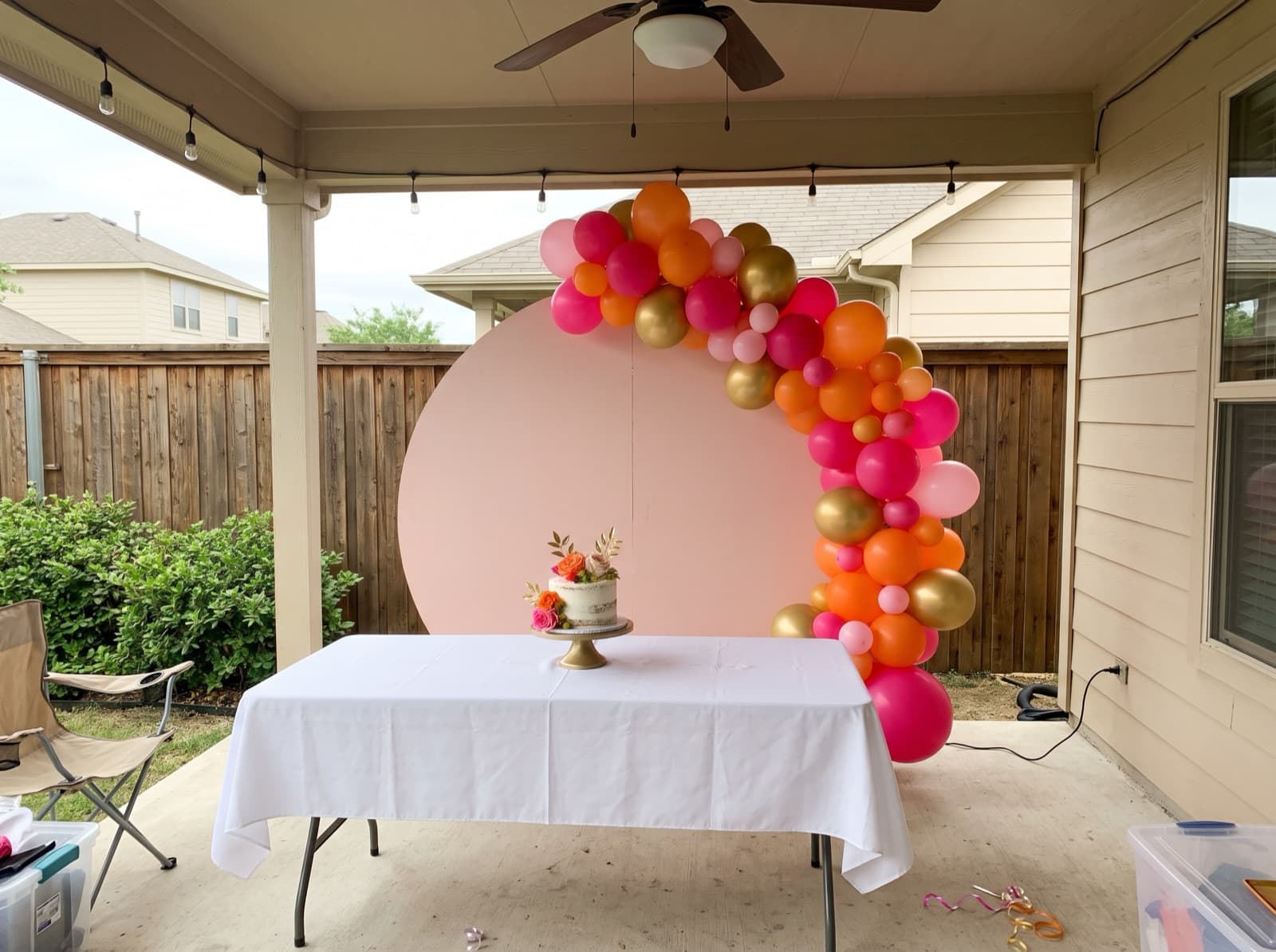 Round blush backdrop with a hot pink, orange and gold balloon garland